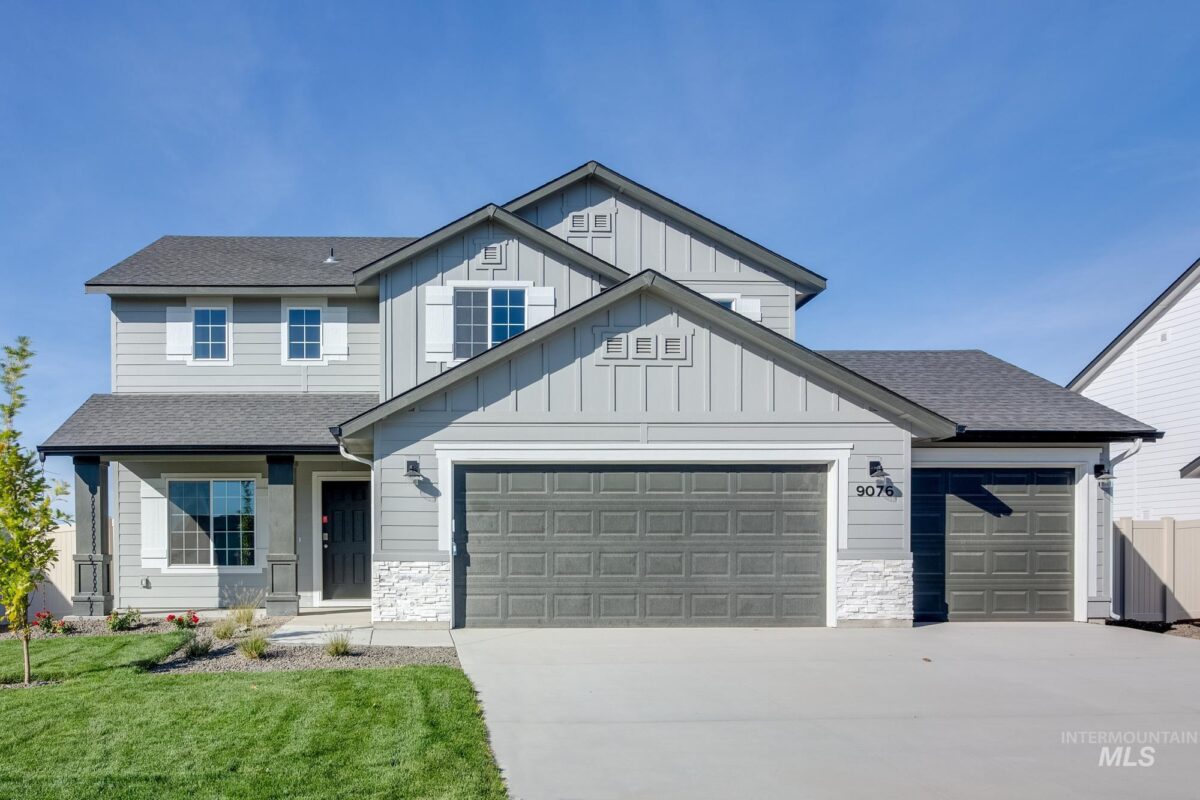 New two-story CBH Home with a three-car garage, modern gray siding, white trim, and a landscaped front yard in Idaho. This beautifully designed home features a covered front porch, black entry door, and large energy-efficient windows, offering curb appeal and contemporary living.